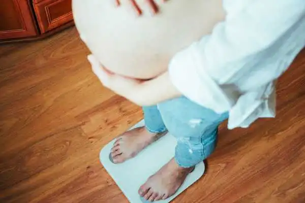 Image of woman weighing herself and experiencing weight gain through pregnancy Stevenage Ware